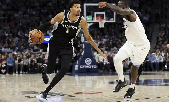 San Antonio Spurs center Victor Wembanyama, left, works around Minnesota Timberwolves forward Julius Randle during the first half of an NBA basketball game Sunday, Dec. 29, 2024, in Minneapolis. (AP Photo/Matt Krohn)