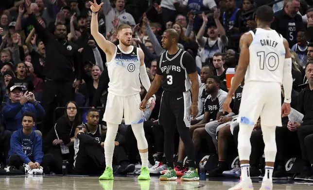 Minnesota Timberwolves guard Donte DiVincenzo, left, celebrates his three-point basket as San Antonio Spurs guard Chris Paul (3) looks on during the first half of an NBA basketball game Sunday, Dec. 29, 2024, in Minneapolis. (AP Photo/Matt Krohn)