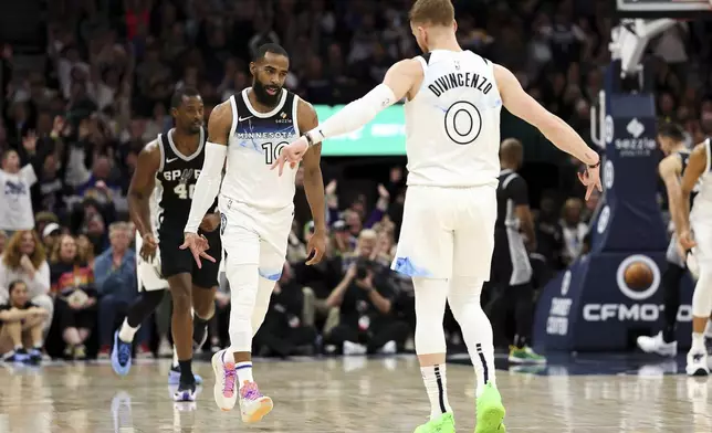 Minnesota Timberwolves guard Mike Conley, left, celebrates his three-point basket with guard Donte DiVincenzo (0) during the first half of an NBA basketball game against the San Antonio Spurs, Sunday, Dec. 29, 2024, in Minneapolis. (AP Photo/Matt Krohn)