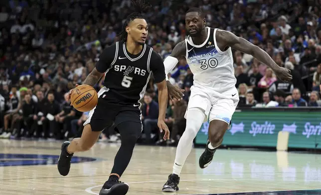 San Antonio Spurs guard Stephon Castle (5) works toward the basket as Minnesota Timberwolves forward Julius Randle (30) defends during the first half of an NBA basketball game Sunday, Dec. 29, 2024, in Minneapolis. (AP Photo/Matt Krohn)