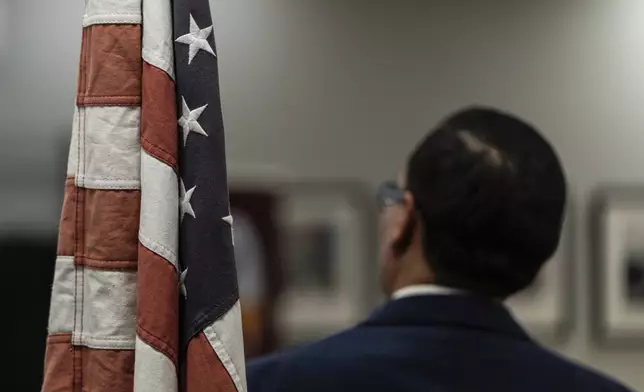 Winston Leiva, community education programs manager at the Coalition for Humane Immigrant Rights, stands next to a U.S. flag while giving a bilingual workshop for immigrants who want to stay in the United States, in Los Angeles, Wednesday, Dec. 4, 2024. (AP Photo/Jae C. Hong)