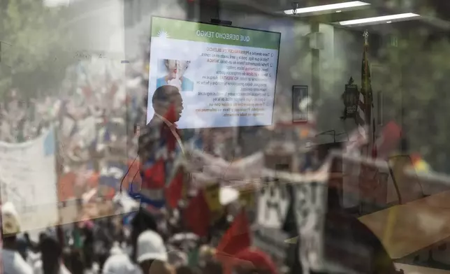 Winston Leiva, community education programs manager at the Coalition for Humane Immigrant Rights, is reflected in the glass of a photo as he gives a bilingual workshop for immigrants who want to stay in the United States, in Los Angeles, Wednesday, Dec. 4, 2024. (AP Photo/Jae C. Hong)