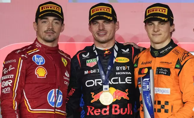 From the left, second-aced Ferrari driver Charles Leclerc of Monaco, first-placed Red Bull driver Max Verstappen of the Netherlands, and third-placed McLaren driver Oscar Piastri of Australia stand on the podium during the Qatar Formula One Grand Prix at the Lusail International Circuit in Lusail, Qatar, Sunday, Dec. 1, 2024. (AP Photo/Altaf Qadri)