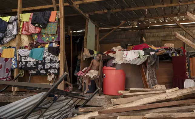 A boy sits in his destroyed home in the Kaweni slum on the outskirts of Mamoudzou in the French Indian Ocean island of Mayotte, Thursday, Dec. 19, 2024, after Cyclone Chido. (AP Photo/Adrienne Surprenant)