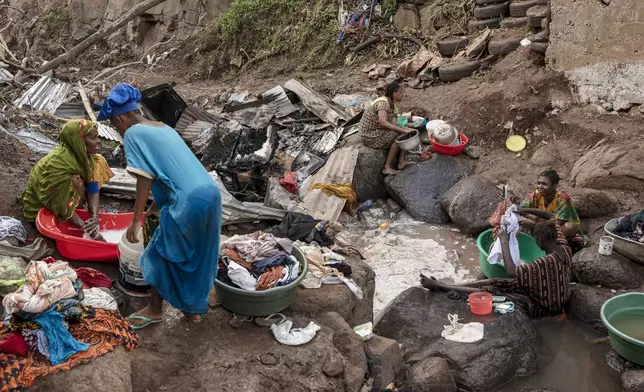 Women wash clothes in a stream in the Kaweni slum on the outskirts of Mamoudzou in the French Indian Ocean island of Mayotte, Thursday, Dec. 19, 2024, after Cyclone Chido. (AP Photo/Adrienne Surprenant)