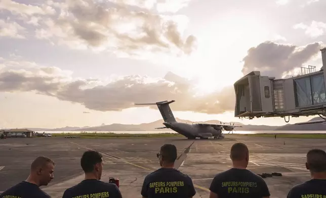 French firemen stand on the tarmac of the airport Wednesday, Dec. 18, 2024 in the French Indian Ocean island of Mayotte. (AP Photo/Adrienne Surprenant)