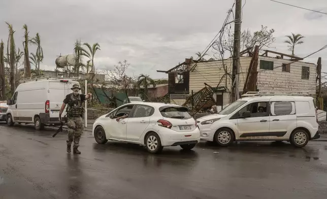 A French officer directs traffic for essential vehicles, in Mamoudzou, Mayotte, Thursday, Dec. 19, 2024. (AP Photo/Adrienne Surprenant)