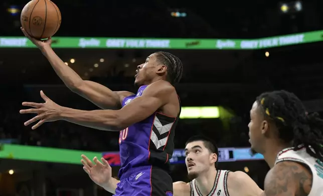 Toronto Raptors guard Ochai Agbaji (30) shoots ahead of Memphis Grizzlies center Zach Edey, center, and guard Ja Morant, right, in the first half of an NBA basketball game Thursday, Dec. 26, 2024, in Memphis, Tenn. (AP Photo/Brandon Dill)