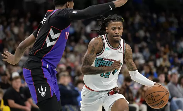 Memphis Grizzlies guard Ja Morant (12) handles the ball against Toronto Raptors guard RJ Barrett, left, in the second half of an NBA basketball game Thursday, Dec. 26, 2024, in Memphis, Tenn. (AP Photo/Brandon Dill)