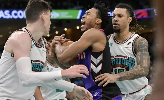 Toronto Raptors forward Scottie Barnes, center, handles the ball between Memphis Grizzlies forwards Jake LaRavia, left, and Brandon Clarke, right, in the first half of an NBA basketball game Thursday, Dec. 26, 2024, in Memphis, Tenn. (AP Photo/Brandon Dill)