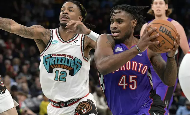 Toronto Raptors guard Davion Mitchell (45) handles the ball ahead of Memphis Grizzlies guard Ja Morant (12) in the first half of an NBA basketball game Thursday, Dec. 26, 2024, in Memphis, Tenn. (AP Photo/Brandon Dill)