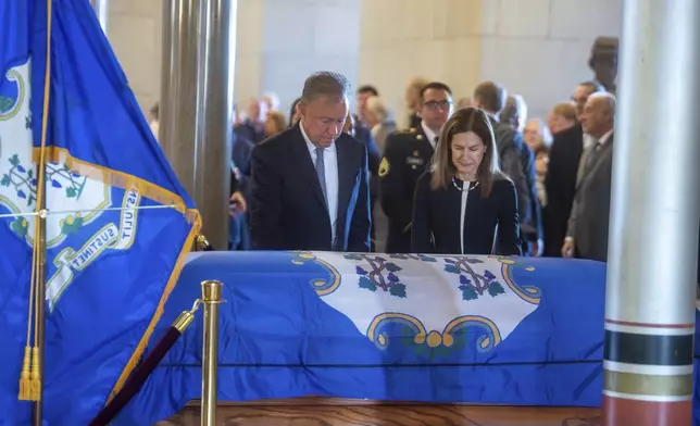 Gov. Ned Lamont and Lt. Governor Susan Bysiewicz pay their respects to the former Governor M. Jodi Rell as she lays in state at the Connecticut State Capitol in Hartford, Conn., Tuesday, Dec. 3, 2024. (Aaron Flaum/Hartford Courant via AP)