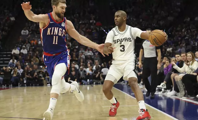 San Antonio Spurs guard Chris Paul (3) drives to the basket against Sacramento Kings forward Domantas Sabonis (11) during the second half of an NBA basketball game in Sacramento, Calif, Sunday, Dec. 1, 2024. (AP Photo/Jed Jacobsohn)