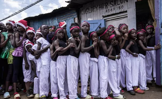 Young girls line up to get their makeup applied at a salon, prior to the start of a Christmas ballet event in Kibera slum, one of the busiest neighborhoods of Kenya's capital, Nairobi, Kenya Saturday, Dec. 21, 2024. (AP Photo/Brian Inganga)