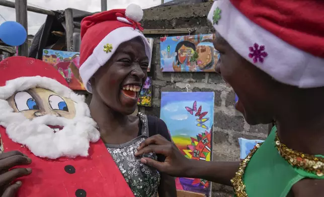 Young dancers share a joke, during a Christmas ballet event in Kibera slum, one of the busiest neighborhoods of Kenya's capital, Nairobi, Kenya Saturday, Dec. 21, 2024. (AP Photo/Brian Inganga)