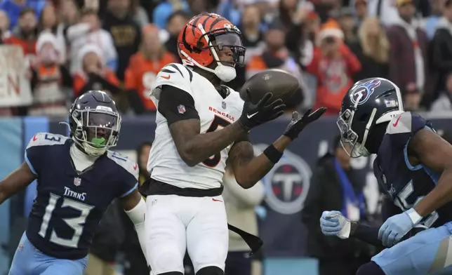 Cincinnati Bengals wide receiver Tee Higgins (5) catches a touchdown pass as Tennessee Titans cornerback Chidobe Awuzie (13) and cornerback Daryl Worley, right, defend during the first half of an NFL football game Sunday, Dec. 15, 2024, in Nashville, Tenn. (AP Photo/George Walker IV)