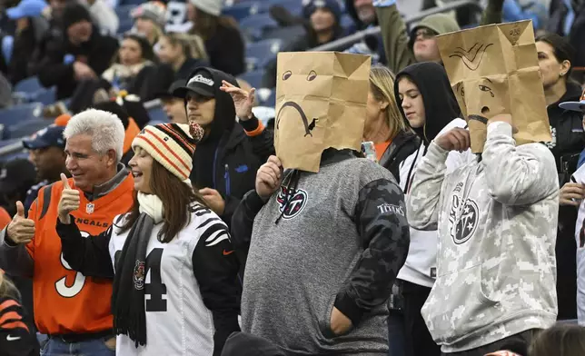 Tennessee Titans fans react next to Cincinnati Bengals fans, at left, in the fourth quarter of an NFL football game Sunday, Dec. 15, 2024, in Nashville, Tenn. (AP Photo/John Amis)