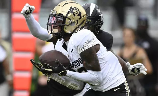 FILE - Colorado wide receiver Travis Hunter (12) catches a pass in the end zone for a 23-yard touchdown reception ahead of Central Florida defensive back Brandon Adams during the first half of an NCAA college football game, Saturday, Sept. 28, 2024, in Orlando, Fla. (AP Photo/Phelan M. Ebenhack, File)