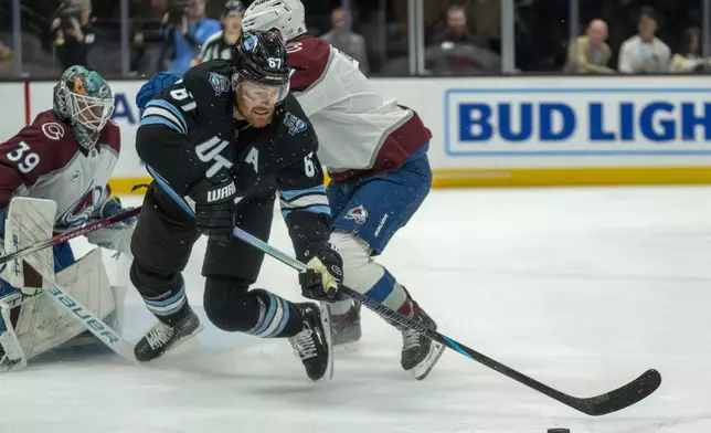 Colorado Avalanche goaltender Mackenzie Blackwood (39) watches as Utah Hockey Club left wing Lawson Crouse (67) goes after the puck, during the first period of an NHL hockey game Friday, Dec. 27, 2024, in Salt Lake City. (AP Photo/Rick Egan)