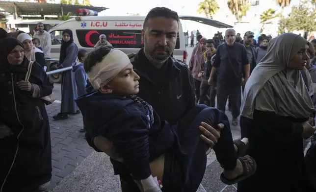 A Palestinian man carries a wounded child, following an Israeli bombardment in Nuseirat, central Gaza, as they arrive at the Al-Aqsa Martyrs hospital in Deir al-Balah, Gaza Strip Wednesday, Dec. 4, 2024. (AP Photo/Abdel Kareem Hana)