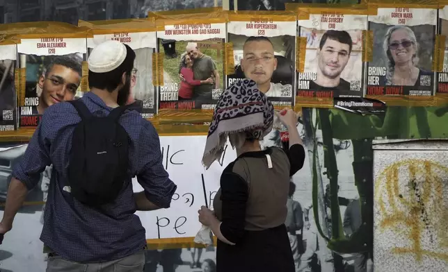 In this picture taken May 25, 2024, people looks at pictures of Hamas hostages, including Itay Svirsky, second from right, in Jerusalem. The Israeli military said Wednesday it had retrieved from Gaza the body of Svirsky who was taken hostage on Oct. 7, 2023, by Hamas and then killed in captivity.(AP Photo/Mahmoud Illean)