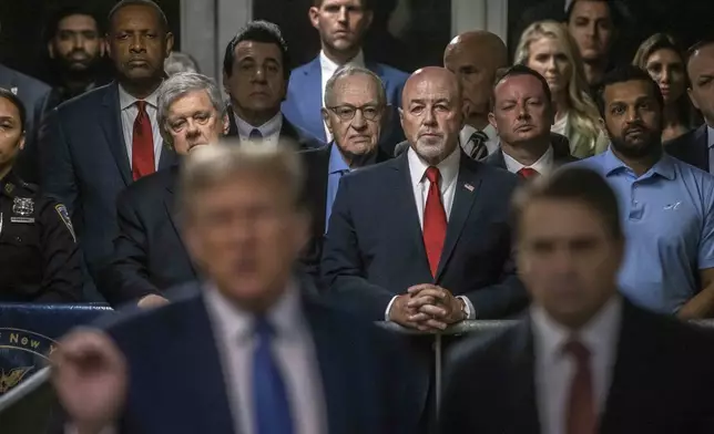 Attorney Alan Dershowitz, background center left in blue shirt, listens to remarks by former President Donald Trump during his ongoing trial at Manhattan Criminal Court in New York, Monday, May 20, 2024. (Dave Sanders/The New York Times via AP, Pool),