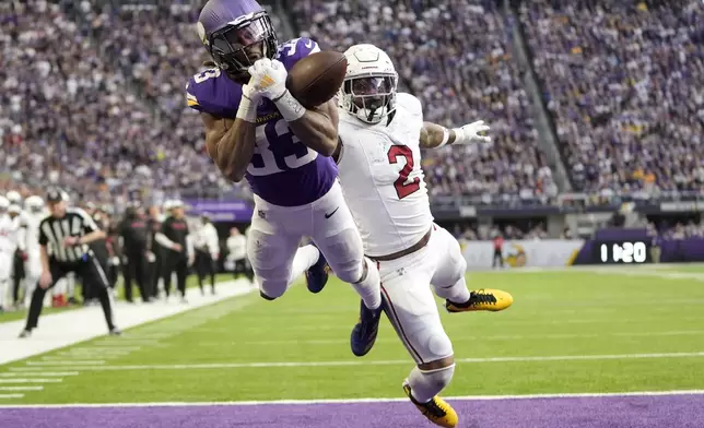 Minnesota Vikings running back Aaron Jones (33) reaches for an incomplete pass ahead of Arizona Cardinals linebacker Mack Wilson Sr. (2) during the second half of an NFL football game Sunday, Dec. 1, 2024, in Minneapolis. (AP Photo/Abbie Parr)