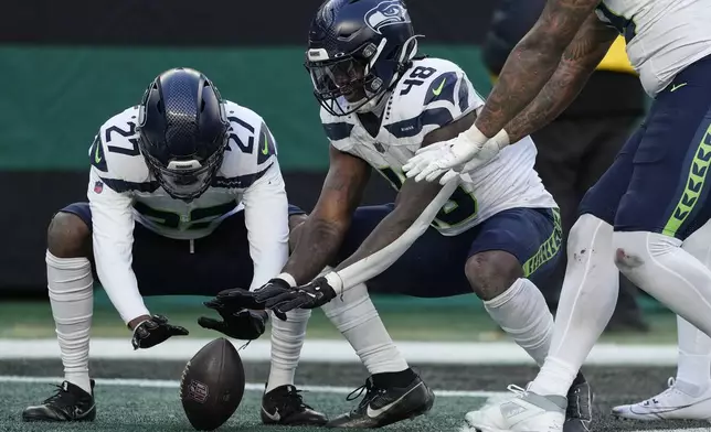 Seattle Seahawks cornerback Riq Woolen (27) and Seattle Seahawks linebacker Tyrice Knight (48) celebrate after Knight recovered a fumble by the New York Jets during the third quarter of an NFL football game, Sunday, Dec. 1, 2024, in East Rutherford, N.J. (AP Photo/Seth Wenig)