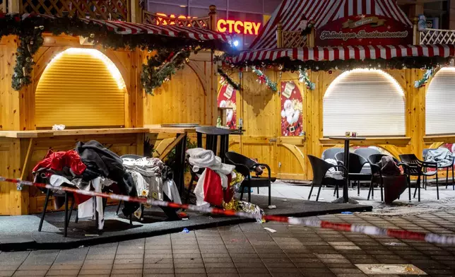 Clothes and blankets lie on chairs at the Christmas market, where a car drove into a crowd on Friday evening, in Magdeburg, Germany, Sunday, Dec. 22, 2024. (AP Photo/Michael Probst)