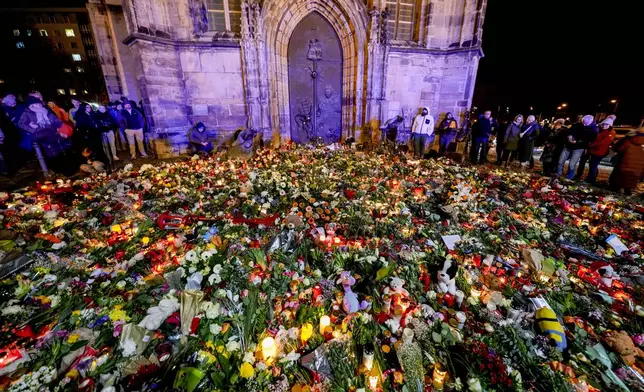 People have laid flowers and candles in front of the Johannis church close to the Christmas market, where a car drove into a crowd on Friday evening, in Magdeburg, Germany, Saturday, Dec. 21, 2024. (AP Photo/Michael Probst)