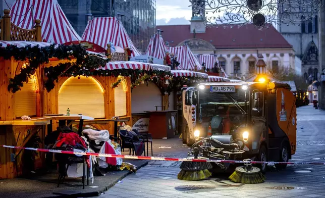 Public workers clean the Christmas Market, where a car drove into a crowd on Friday evening, in Magdeburg, Germany, is empty on Sunday morning , Dec. 22, 2024. (AP Photo/Michael Probst)