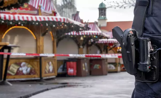 A police officer guards the Christmas Market, where a car drove into a crowd on Friday evening, in Magdeburg, Germany, on Sunday morning, Dec. 22, 2024. (AP Photo/Michael Probst)