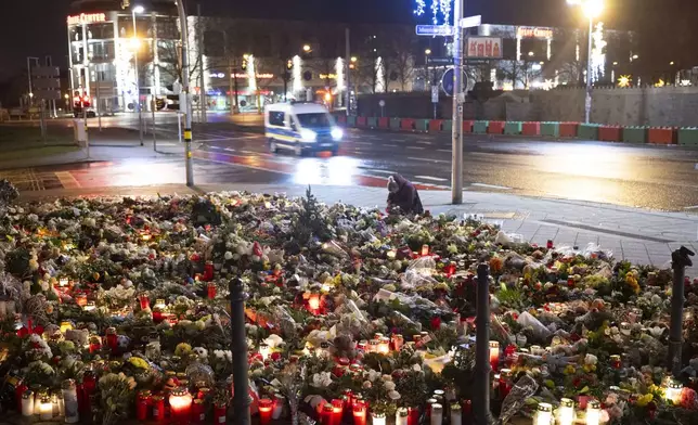 Candles, flowers and wreaths sit in front of the entrance to St. John's Church early Sunday, Dec. 22, 2024, in Magdeburg, Germany, after a car drove into a crowd at a Christmas market on Friday, Dec. 20. (Sebastian Kahnert/dpa via AP)