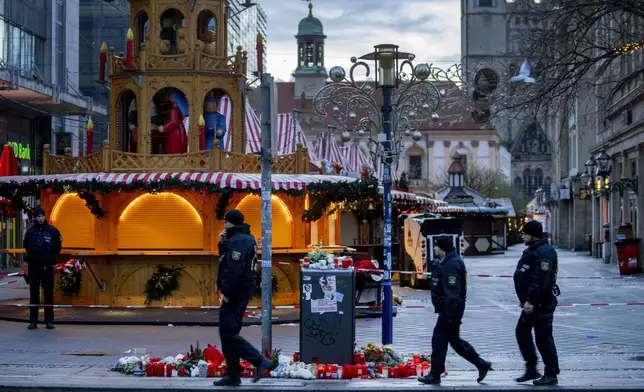 Policemen walk past the Christmas Market, where a car drove into a crowd on Friday evening, in Magdeburg, Germany, is empty on Sunday morning , Dec. 22, 2024. (AP Photo/Michael Probst)