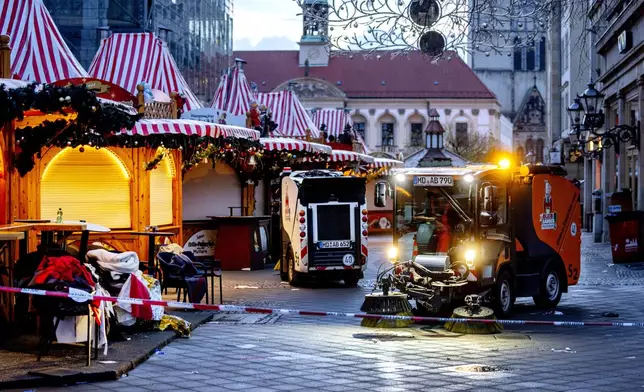 Public workers clean the Christmas Market, where a car drove into a crowd on Friday evening, in Magdeburg, Germany, is empty on Sunday morning , Dec. 22, 2024. (AP Photo/Michael Probst)