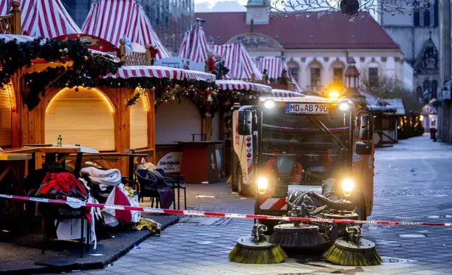 Public workers clean the Christmas Market, where a car drove into a crowd on Friday evening, in Magdeburg, Germany, on Sunday morning , Dec. 22, 2024. (AP Photo/Michael Probst)