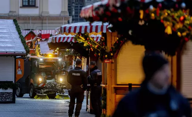 Public workers clean the Christmas Market, where a car drove into a crowd on Friday evening, in Magdeburg, Germany, is empty on Sunday morning , Dec. 22, 2024. (AP Photo/Michael Probst)