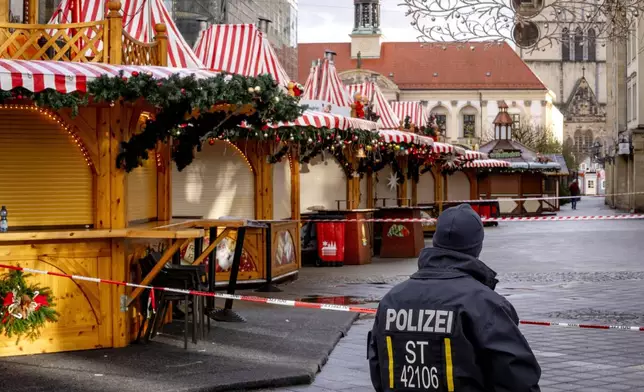 A police officer guards the Christmas Market, where a car drove into a crowd on Friday evening, in Magdeburg, Germany, on Sunday morning, Dec. 22, 2024. (AP Photo/Michael Probst)