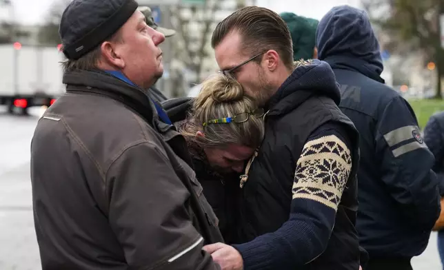 People embrace as they mourn the victims near the Christmas Market, where a car drove into a crowd on Friday evening, in Magdeburg, Germany, Sunday, Dec. 22, 2024. (AP Photo/Ebrahim Noroozi)