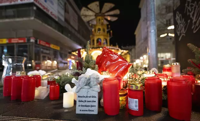 Candles sit in front of the Christmas market early Sunday, Dec. 22, 2024, in Magdeburg, Germany, after a car drove into a crowd at the market on Friday, Dec. 20. (Sebastian Kahnert/dpa via AP)