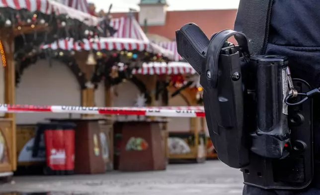 A police officer guards the Christmas Market, where a car drove into a crowd on Friday evening, in Magdeburg, Germany, Sunday morning , Dec. 22, 2024. (AP Photo/Michael Probst)