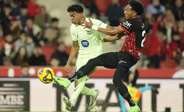 Barcelona's Lamine Yamal, left challenges for the ball with Mallorca's Johan Mojica during a Spanish La Liga soccer match between Mallorca and Barcelona at the Son Moix stadium in Palma de Mallorca, Spain, Tuesday, Dec. 3, 2024. (AP Photo/Jose Breton)