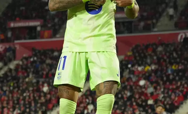 Barcelona's Raphinha touches the club logo on his shirt after after scoring his side's third goal during a Spanish La Liga soccer match between Mallorca and Barcelona at the Son Moix stadium in Palma de Mallorca, Spain, Tuesday, Dec. 3, 2024. (AP Photo/Jose Breton)