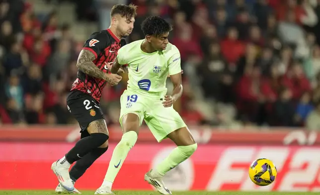 Mallorca's Pablo Maffeo, left, challenges for the ball with Barcelona's Lamine Yamal during a Spanish La Liga soccer match between Mallorca and Barcelona at the Son Moix stadium in Palma de Mallorca, Spain, Tuesday, Dec. 3, 2024. (AP Photo/Jose Breton)