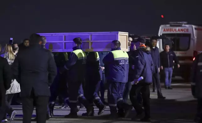 Workers carry a coffin with a body of a victim from a medical plane after the Azerbaijani Airline crashed, near the Kazakhstani city of Aktau, upon their arrival at the Heydar Aliyev International Airport outside Baku, Azerbaijan, Thursday, Dec. 26, 2024. (AP Photo)