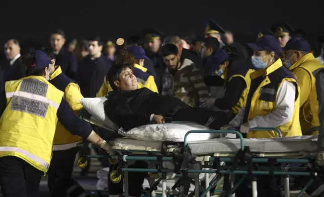 Wounded passengers of the Azerbaijani Airline's plane crashed near the Kazakhstani city of Aktau, are transported from a medical plane at the Heydar Aliyev International Airport outside Baku, Azerbaijan, Thursday, Dec. 26, 2024. (AP Photo)