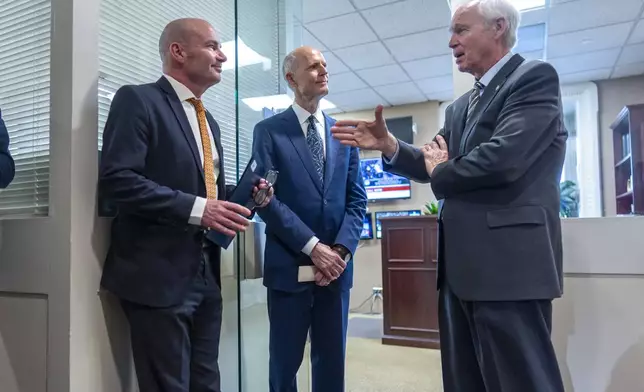 Sen. Mike Lee, R-Utah, Sen. Rick Scott, R-Fla., and Sen. Ron Johnson, R-Wis., confer before joining other conservative Republicans to complain to reporters about the interim spending bill being crafted to avoid a shutdown of federal agencies, at the Capitol in Washington, Wednesday, Dec. 18, 2024. (AP Photo/J. Scott Applewhite)