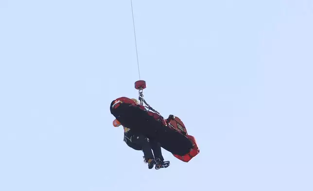 Italy's Pietro Zazzi is lifted by medical staff to an helicopter after crashing during an alpine ski, men's World Cup downhill training, in Bormio, Italy, Friday, Dec. 27, 2024. (AP Photo/Marco Trovati)