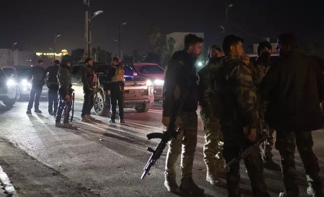 Syrian fighters gather during the night on a street in Damascus, Syria, Wednesday, Dec. 25, 2024. (AP Photo/Leo Correa)