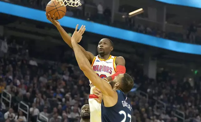 Golden State Warriors forward Jonathan Kuminga, top, drives to the basket against Minnesota Timberwolves center Rudy Gobert (27) during the first half of an NBA basketball game in San Francisco, Sunday, Dec. 8, 2024. (AP Photo/Tony Avelar)